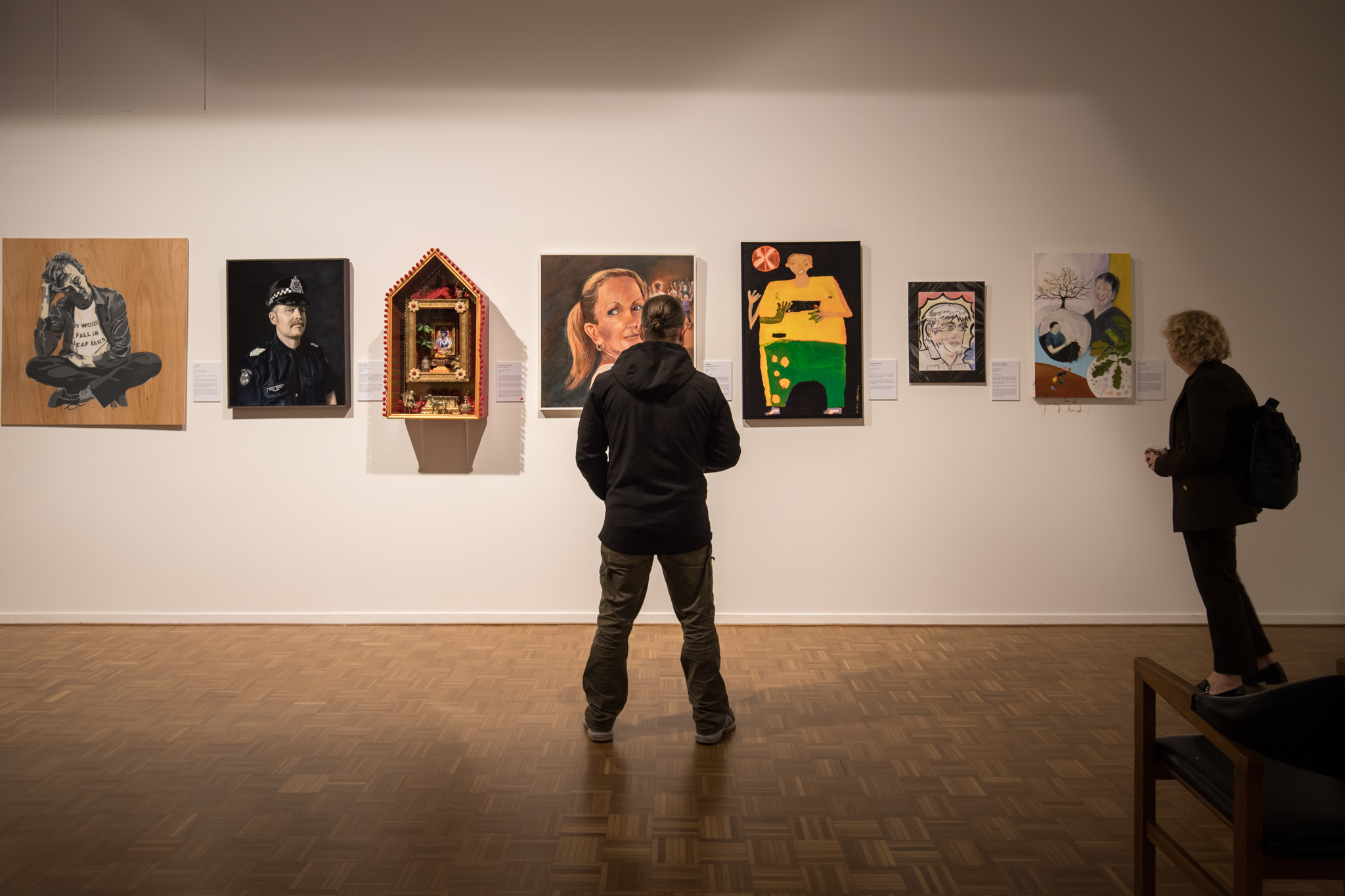 Man standing infront of portraits in an art gallery